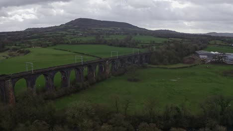 Eine-Luftaufnahme-Des-Viadukts-Einer-Großen-Buxton-Eisenbahnbrücke-Im-Derbyshire-Peak-District-Nationalpark,-Einer-Belebten-Bahnstrecke-In-Der-Wunderschönen-Landschaft-Von-Derbyshire,-Luftaufnahmen