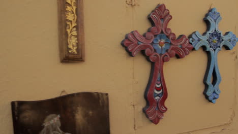 Colorful-souvenir-christian-crosses-hang-on-an-orange-wall