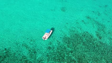 Drone-flying-over-boat-in-blue-green-waters-in-Cayman-Islands