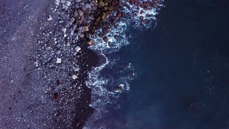 Aerial-topdown-shot-of-rocky-coast-with-little-pier-and-waves-crushing-the-coast,-Paul-do-Mar,-Madeira,-Portugal