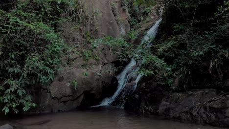 Sideways-sliding-movement-showing-a-waterfall-in-the-tropical-mountain-forest-within-the-city-of-Rio-de-Janeiro-revealing-wider-surrounding-with-a-small-pond