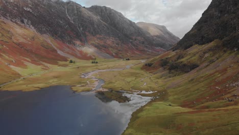 Volando-Lentamente-Sobre-Un-Valle-Montañoso-Y-Un-Lago-Rodeados-A-Ambos-Lados-Por-Montañas-Escocesas-En-El-área-De-Glencoe-En-Escocia