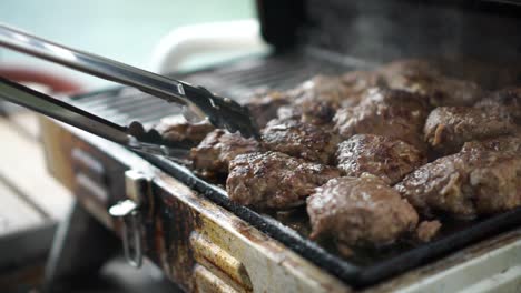 Chef-flips-home-made-beef-burgers-on-bbq---close-up