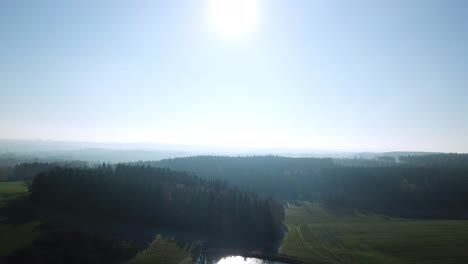Luftaufstieg-über-Wald-Und-See-In-Der-Morgensonne