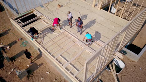 A-drone-shot-slowly-craning-up-to-view-on-construction-framers-putting-up-walls-on-a-new-home-in-the-process-of-being-built
