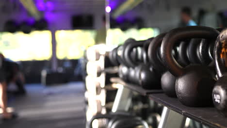 A-rack-of-weights-and-kettlebells-in-a-gym-with-people-defocused-working-out-and-training-in-the-background