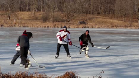 Eine-Folgende-Aktionsaufnahme-Einer-Gruppe-Von-Freunden,-Die-Teichhockey-Auf-Einem-Zugefrorenen-See-Spielen