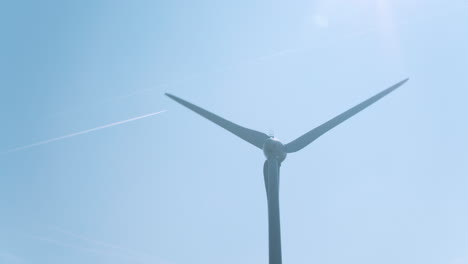 Windmühlenturbinen-Drohnen-Dolly-Aufnahme-Vor-Blauem-Himmel-Mit-Flugzeugspuren-Im-Hintergrund