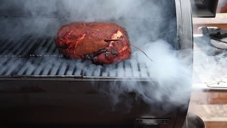 Opening-the-lid-of-a-smoker-to-reveal-heavy-smoke-and-a-pork-butt-before-closing-the-lid-again