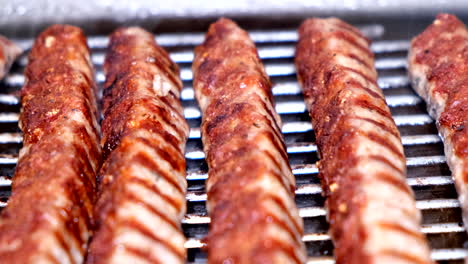 Closeup-slowmo-of-sausage-kebabche-on-a-barbecue-grill-in-a-kitchen