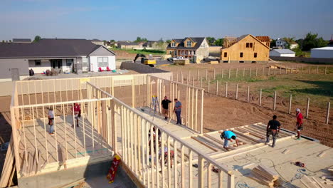 A-drone-shot-slowly-pushing-in-on-construction-framers-putting-up-walls-on-a-new-home-in-the-process-of-being-built