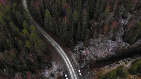 Aerial-view-of-road-in-forest-going-over-a-small-river