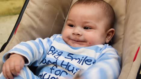 CLOSE-UP-clip-of-infant-in-blue-striped-onesie-smiling-at-somebody-off-camera