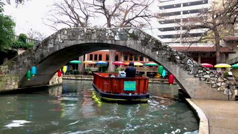 Riverboats-patrol-the-Riverwalk-routes-to-ferry-visitors-around-the-area's-restaurants,-sights,-and-sounds