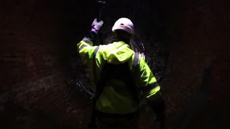 A-sewer-district-worker-leads-the-path-with-a-light-down-an-old-19th-century-sewage-tunnel