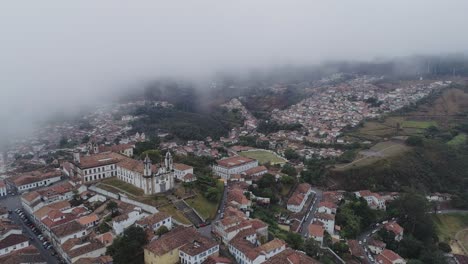 Drone-image-of-an-historical-city-going-up-into-the-clouds,-minas-gerais,-Brazil