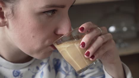 Big-sip-of-flat-white-coffe-from-a-glass,-closeup-of-girl-lips-and-face