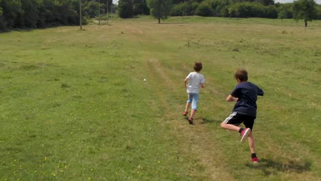 Kinder-Laufen-Und-Spielen-Auf-Der-Grünen-Wiese---Zeitlupe-Aus-Der-Luft
