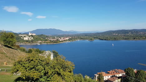 Aerial-View-Of-Lake-Maggiore-From-Rocca-Of-Arona-Castle-Of-Angera-In-The-Distance-And-Sailboat-Sailing
