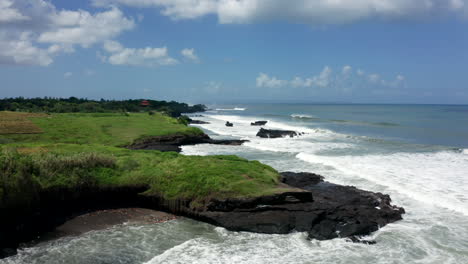 Aerial-drone-footage,-coastline-with-black-rocks-in-Bali