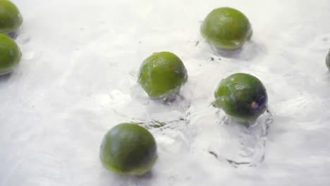SLOMO-of-Limes-Falling-into-Water-on-White-Backdrop