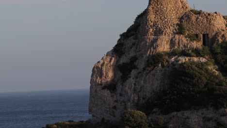 Tilt-down-shoot-of-a-rocky-mountain-summit-over-the-Mediterranean-sea-with-birds-flying-around