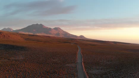 Drone-shot-of-a-dirt-road-at-sunset-in-the-Atacama-Desert,-Chile,-South-America