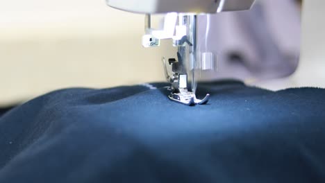 close-up-shot-of-a-sewing-machine-that-is-sewing-a-zig-zag-pattern-onto-blue-fabric-using-white-thread
