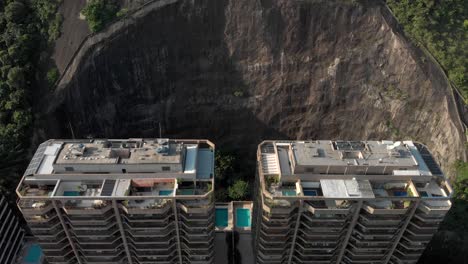 Slow-aerial-approach-of-residential-high-rise-condominiums-residing-in-a-partly-cut-out-mountain-side-revealing-the-pools-and-tennis-courts-behind