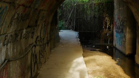 Una-Toma-Caminando-Por-Un-Túnel-Corto-Con-Grafitis-A-Los-Lados
