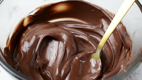Revolviendo-El-Chocolate-Derretido-Con-Una-Cuchara-En-Un-Recipiente-De-Vidrio-Y-Mojando-La-Fresa