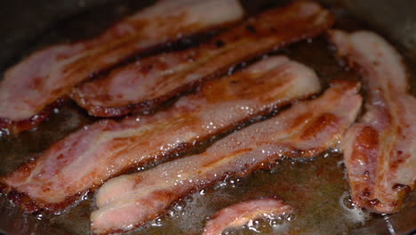 Slow-motion-clip-of-delicious-bacon-being-fried-in-a-stainless-steel-pan