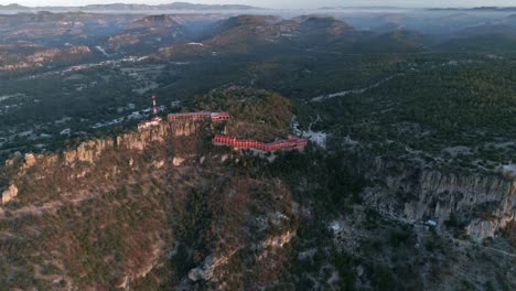 Aerial-wide-shot-a-the-Urique-Canyon-and-a-hotel-at-sunrise-in-Divisadero,-Copper-Canyon-Region,-Chihuahua