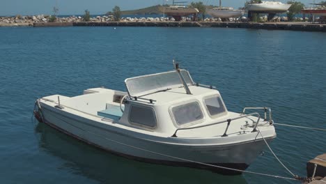 Small-plastic-cruiser-with-aluminium-windows-moored-at-quiet-seaside-harbor