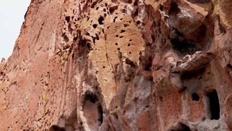 Close-up,-Pan-up-shot-of-a-mountain-wall,-at-Bandelier-National-Monument,-on-a-cloudy-day,-in-Santa-Fe,-New-Mexico,-USA