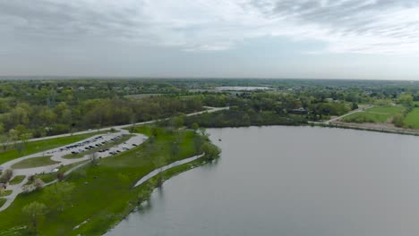 Drone-slow-horizontal-movement-across-the-horizon-of-small-lake-in-suburban-public-park