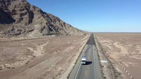 Aerial,-reverse,-drone-shot,-rising-in-front-of-a-camper-truck,-driving-on-a-desert-road,-on-a-sunny-day,-on-San-Felipe-highway,-in-Baja,-California,-Mexico