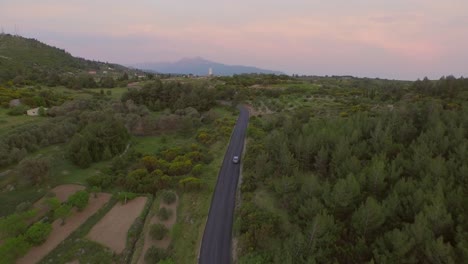 Luftaufnahme:-Ein-Auto-Fährt-Bei-Sonnenuntergang-Durch-Die-Berge-Von-Samos,-Griechenland