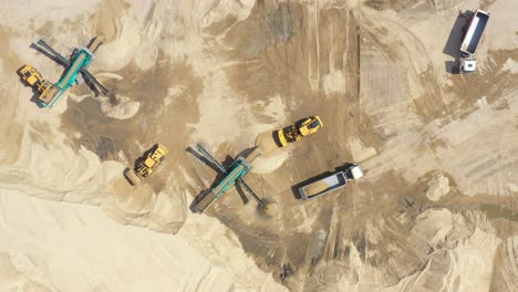 Aerial-view,-machinery-working-at-clay-quarry,-heavy-loaders,-large-trucks,-bulldozers,-excavators,-Sand-quarry,-Mining,-Truck-takes-raw-materials-from-the-quarry,-Large-clay-warehouse