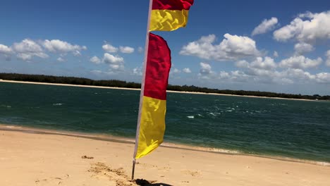 Rote-Und-Gelbe-Rettungsflaggen-Am-Strand-Von-Caloundra-An-Einem-Windigen-Tag