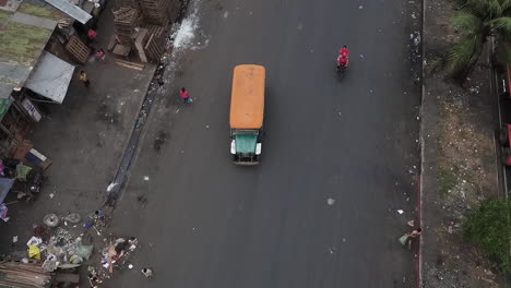 Aerial-Shot-Of-A-Jeepney-Travelling-On-A-Busy,-Dirty-Road-Of-Manila-Philippines