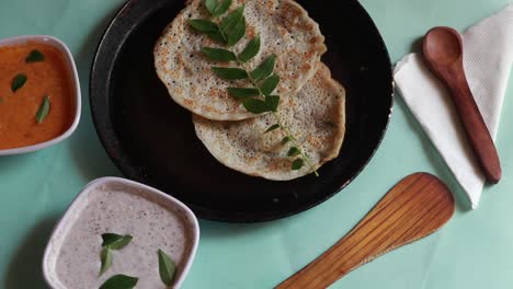Rotating-Oothappam---Dosa---South-Indian-breakfast-using-rice-lentil-and-vegetables-served-with-coconut-chutneyisolated-on-green-background