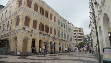 Time-lapse-of-Senado-Square-with-colorfully-painted-buildings-and-tourists-passing-by-on-a-cloudy-overcast-day-in-Macau,-Macau-SAR,-China