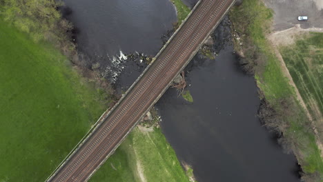 Aerial-Birds-Eye-View-of-Train-Tracks-Crossing-River-in-Yorkshire,-England-with-Spiral-Reveal