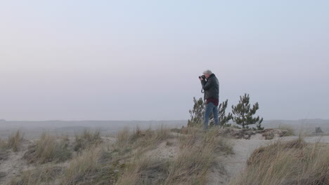 Close-up-shot-of-a-landscape-photographer-man-taking-photos-in-nature-at-sunset-or-sunrise