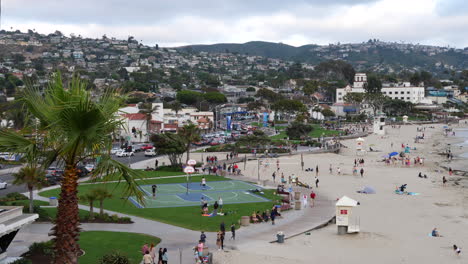 Many-people-and-tourists-on-the-coast-enjoying-the-city-and-ocean-at-Laguna-Beach,-California-on-a-cloudy-day