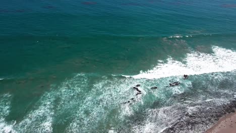 Aerial,-drone-shot-of-Malibu-beach-and-Pacific-coast-highway,-overlooking-houses,-and-crashing-waves-on-the-coast,-in-California,-USA