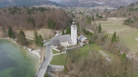 Punto-De-Vista-De-Drones-Alrededor-Del-Puente-Y-La-Iglesia-Desde-El-Lago-Bohinj,-Eslovenia