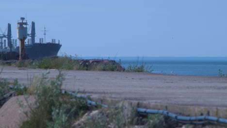 Forest---product-carrier-ship-arriving-at-Port-of-Liepaja-in-hot-summer-day,-distant-medium-shot-from-fort-pier
