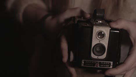 Girl's-hands-open-Box-Brownie-camera-case-and-reveals-to-camera-outdoors-low-light